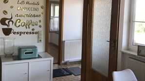 Een kamer met een wit kastje, een klok en een muur met tekst over koffie.