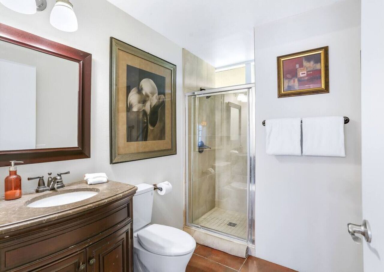 A bathroom with a sink, toilet, and glass shower enclosure.