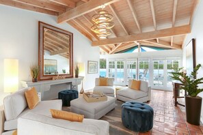 A spacious living area with a high ceiling, a fireplace, and a view of a pool.