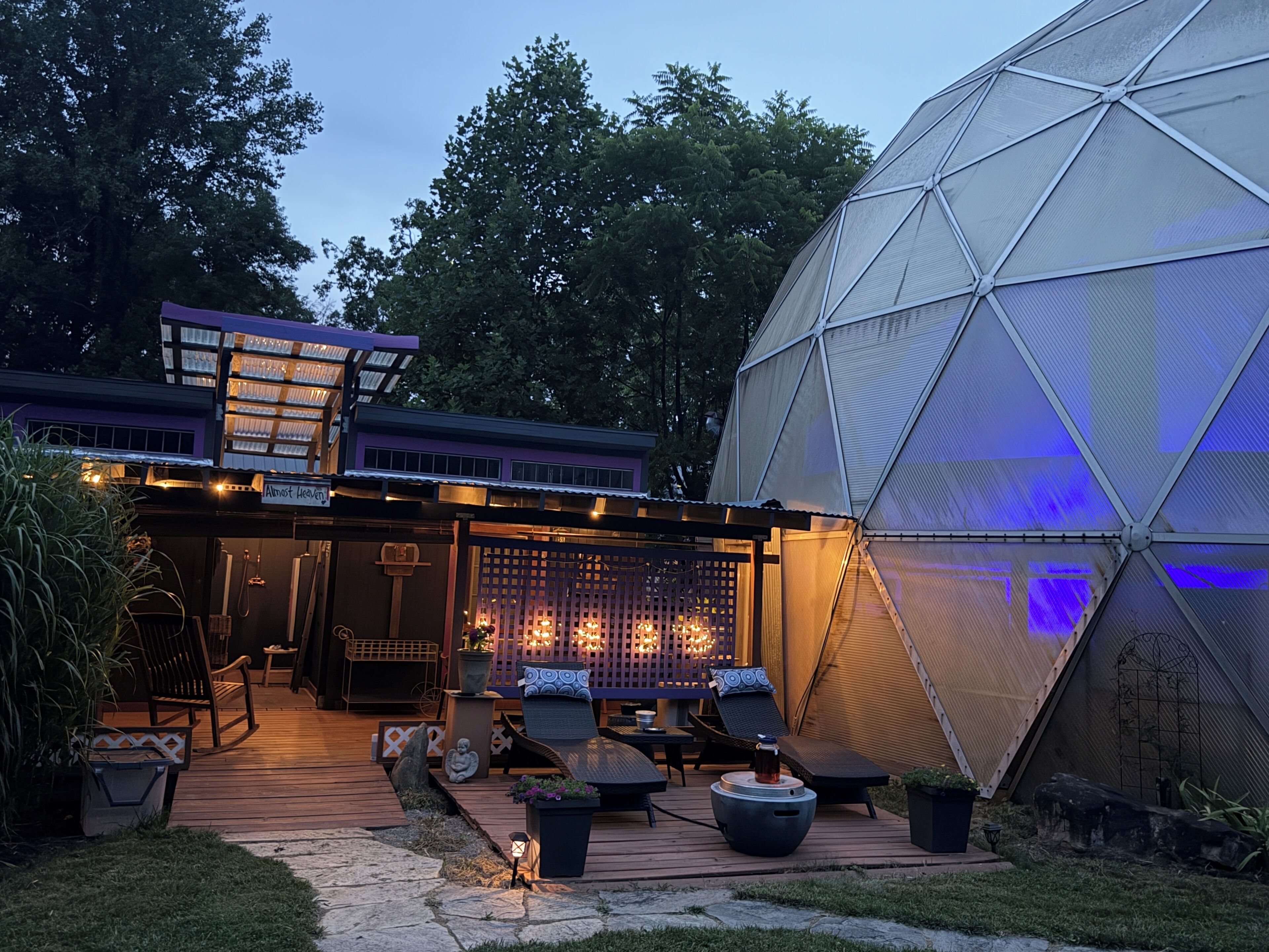 Una estructura de invernadero con cúpula, una terraza con asientos exteriores y un área cubierta con luces.
