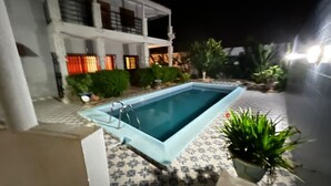 A rectangular swimming pool with a light blue edge, surrounded by a tiled patio. - DIOUF HOUSE (Saly)