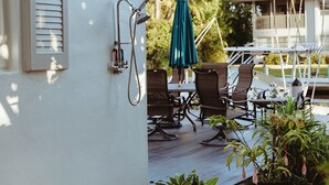 Een terras met tuinmeubilair, een groene parasol en potplanten.