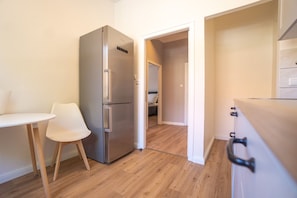 Compact kitchen with a stainless steel refrigerator and dining table, perfect for small living spaces.