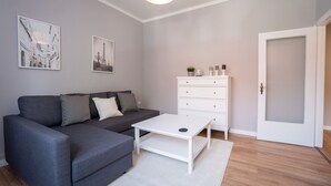 Una sala moderna con un sofá gris, una mesa de centro blanca y un aparador blanco.