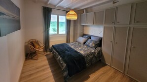 Een slaapkamer met een bed, een stoel, een raam en inbouwmeubels.