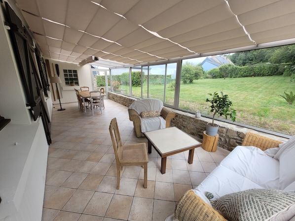 A covered patio area with a dining table and chairs, a sofa, and a potted plant. - Family beach house (Ploubazlanec)