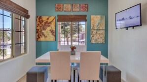 A dining area with a teal wall, a large window, and a flat-screen TV on the wall. - Az morning glory 4bedroom home (Buckeye)