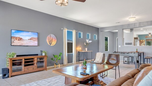 A modern living room with a sofa, coffee table, TV, and a foosball table. - Az morning glory 4bedroom home (Buckeye)
