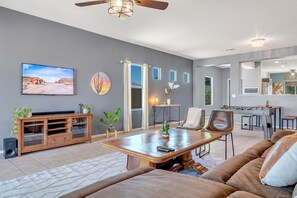 A modern living room with a sofa, coffee table, TV, and a foosball table. - Az morning glory 4bedroom home (Buckeye)