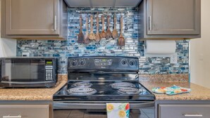 A kitchen with a black stove, a microwave, and wooden utensils hanging on the wall. - Az morning glory 4bedroom home (Buckeye)