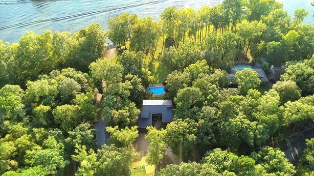 Vista aérea de una propiedad rodeada de árboles frondosos, con piscina y una construcción pequeña.