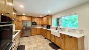 Una cocina moderna con armarios de madera, electrodomésticos de acero inoxidable y un ventanal con vistas al verdor.