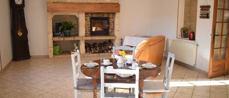 A dining area with a fireplace, a clock, and a mirror on the wall.