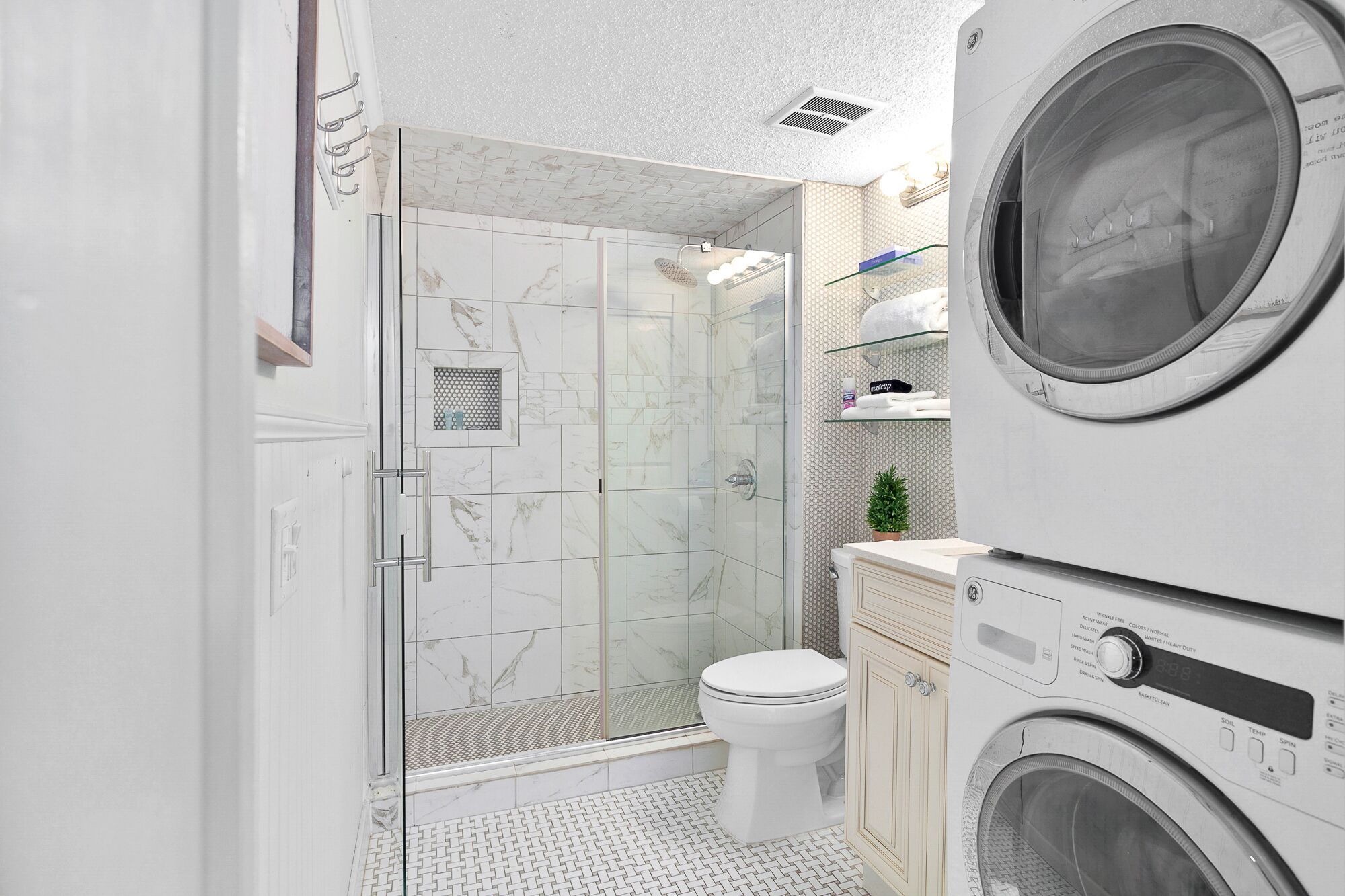 Un baño moderno con ducha de vidrio, inodoro y lavadora integrada.