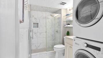 Un baño moderno con ducha de vidrio, inodoro y lavadora integrada.