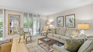 Een woonkamer met een bank, fauteuils, een salontafel en een vloerkleed met dessin.