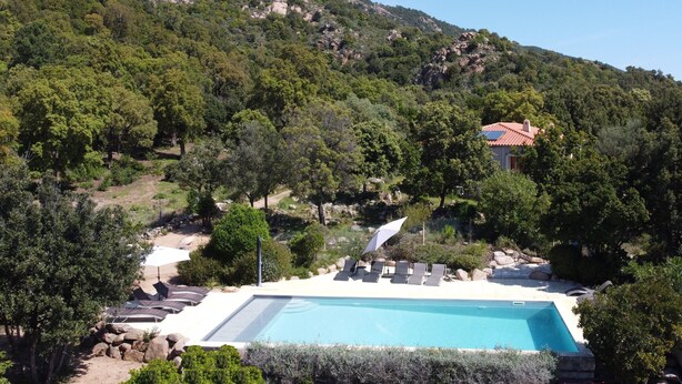 A pool area with lounge chairs and umbrellas, surrounded by trees and a mountain backdrop. - Semi-detached mini-villa in small family residence (San-Gavino-Di-Carbini)