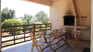 An outdoor patio with a wooden table, chairs, and a pizza oven. - Semi-detached mini-villa in small family residence (San-Gavino-Di-Carbini)