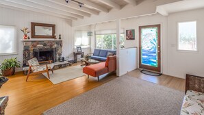 A spacious living room with a stone fireplace, a blue sofa, and a patterned rug. - Winter rental across from the ocean in exclusive San Diego beach community... (Encinitas)