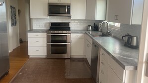 A modern kitchen with white cabinets, stainless steel appliances, a double oven, a microwave, and a sink. - Winter rental across from the ocean in exclusive San Diego beach community... (Encinitas)
