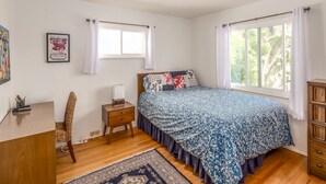 A bedroom with a bed, a desk, a chair, a nightstand, a window, and a view of trees. - Winter rental across from the ocean in exclusive San Diego beach community... (Encinitas)