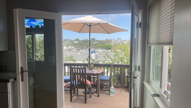 A room with a sliding glass door leading to an outdoor patio with a table, chairs, and a large umbrella. - Winter rental across from the ocean in exclusive San Diego beach community... (Encinitas)
