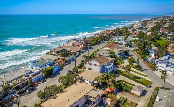An aerial view of a coastal residential area with houses, streets, and a beach. - Winter rental across from the ocean in exclusive San Diego beach community... (Encinitas)