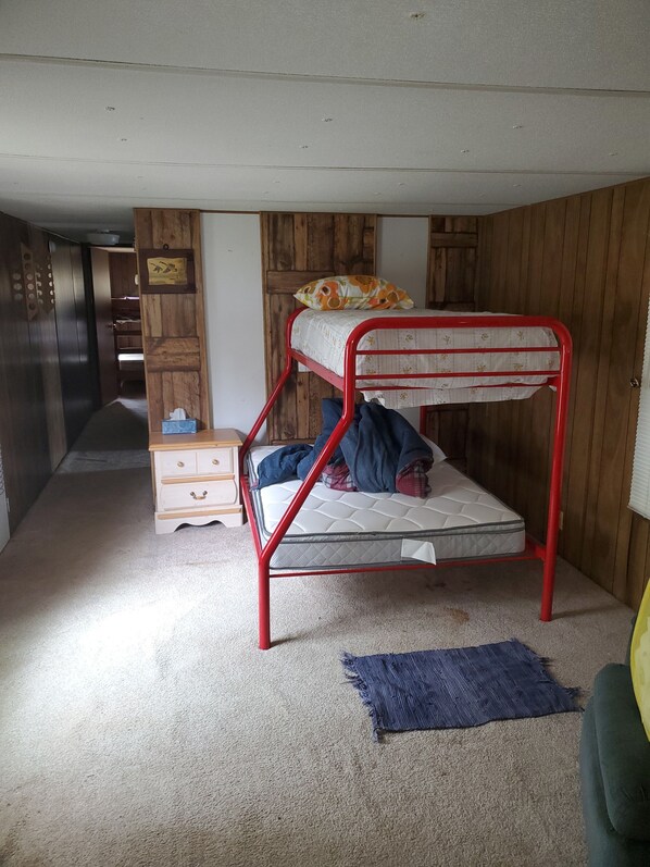 A bunk bed with a red frame, a wooden wardrobe, a small dresser, and a blue rug. - Lakeside rental (Jonesville)