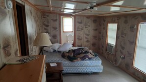 Una habitación pequeña con una cama, un escritorio, una lámpara y una ventana.