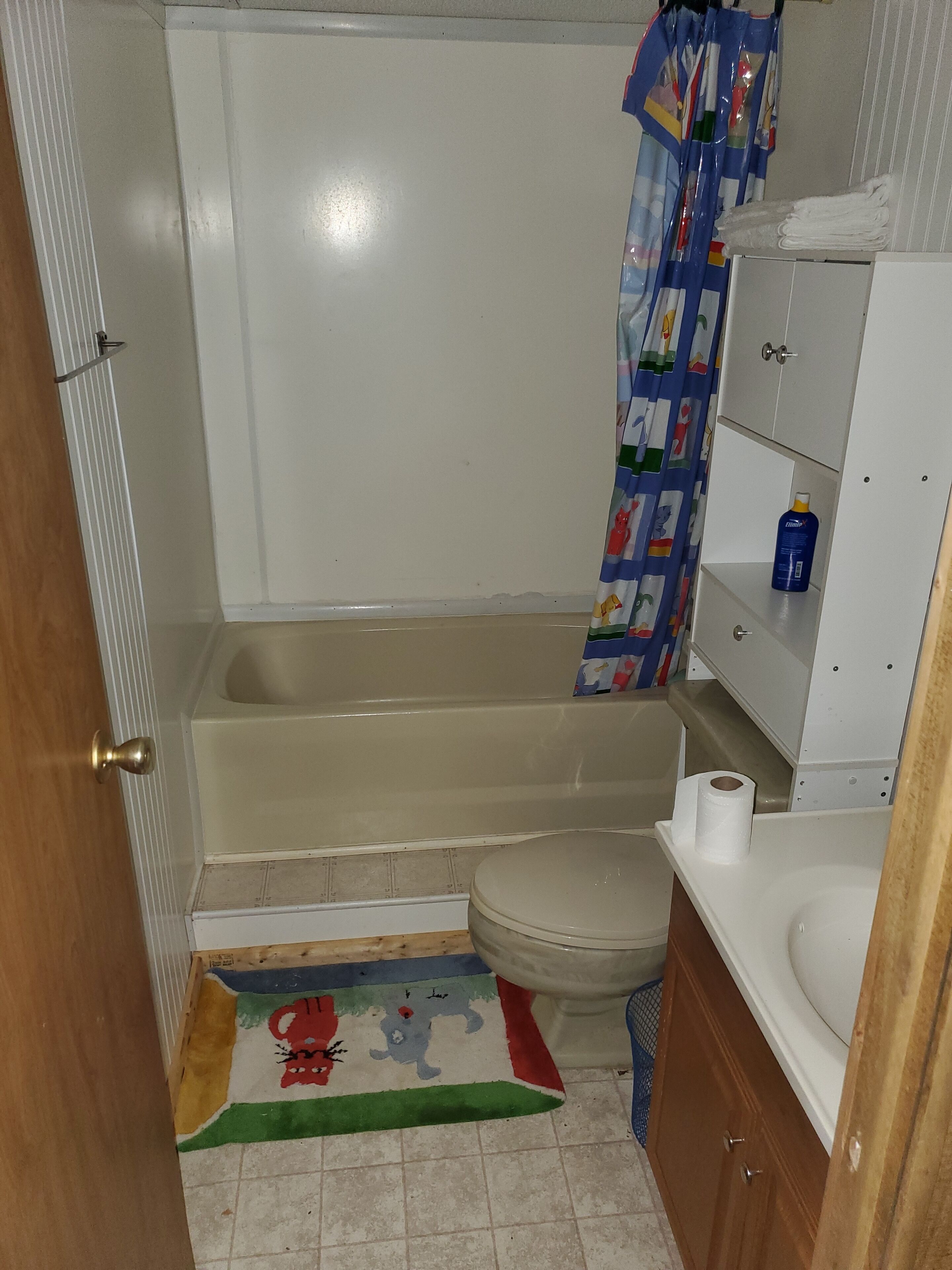 Een bad/douchecombinatie, handdoeken, toiletpapier