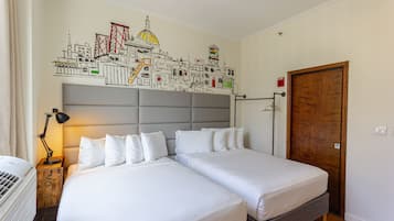 Habitación de hotel con dos camas, un mural con vista a la ciudad en la pared, una mesita de noche de madera con una lámpara y una puerta de madera.