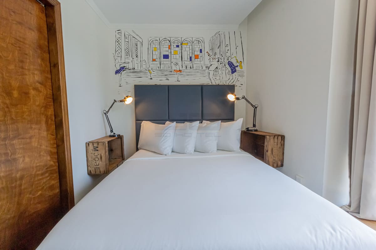 A hotel room with a large bed, wooden headboard, and two bedside lamps.