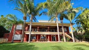 Un edificio de dos pisos con balcón, rodeado de palmeras.
