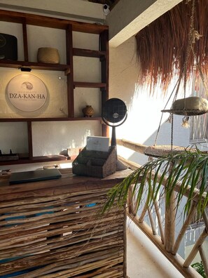 A room with a wooden desk, a laptop, a basket, a hanging plant, and a wall-mounted sign. - Sunset Condo Puerta al Mar (Isla Mujeres)