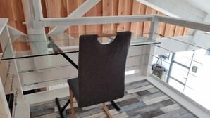 Ein modernes Interieur mit Glastrennwand, einem grau gepolsterten Sessel und Holzboden.