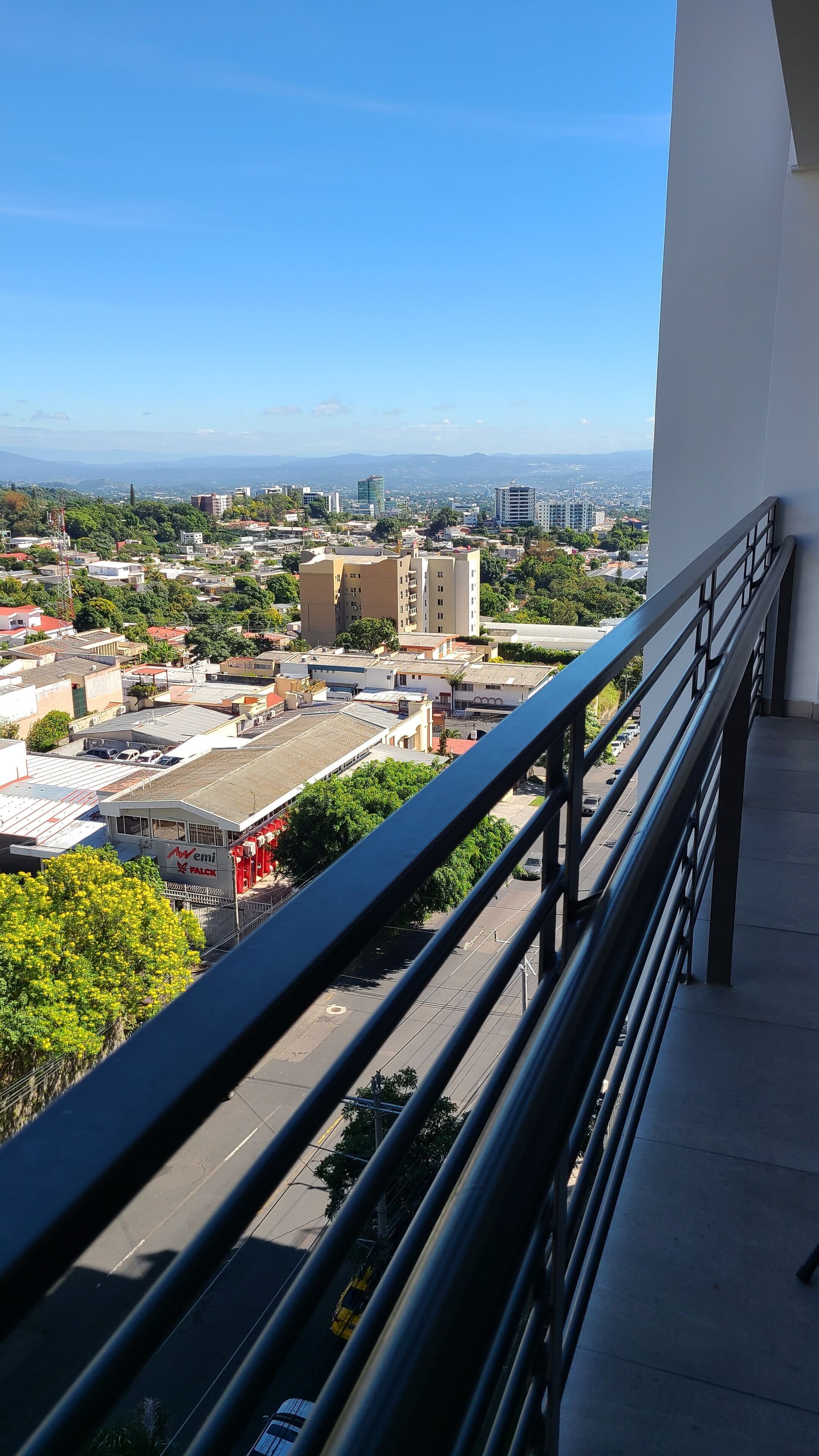 A balcony with a view of a cityscape, including buildings and a clear sky.