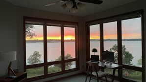A room with large windows, a ceiling fan, a desk, and a chair. - Luxurious Lakefront  BB Corner Condo.
Panoramic lake views & 6 waterpark passes. (Arnolds Park)