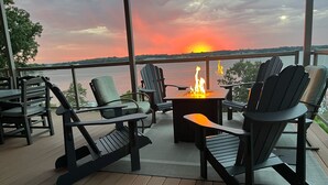 A deck with outdoor seating, a fire feature, and a view of the sunset over the water. - Luxurious Lakefront  BB Corner Condo.
Panoramic lake views & 6 waterpark passes. (Arnolds Park)