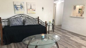 Une chambre à coucher avec un lit, une table basse en verre et deux tableaux accrochés au mur.