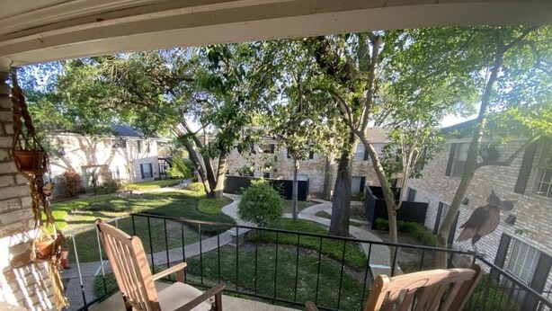Un balcon avec deux chaises en bois et une plante suspendue.