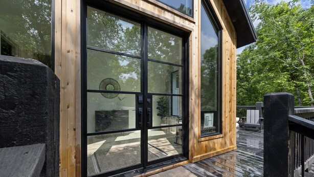 Une terrasse en bois avec une porte vitrée donnant sur une pièce.