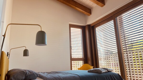 Une chambre à coucher avec un lit, une lampe de bureau et une fenêtre avec des stores.