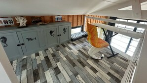 Une chambre avec un lit superposé, un plancher en bois et une armoire décorée d’autocollants représentant des poissons.