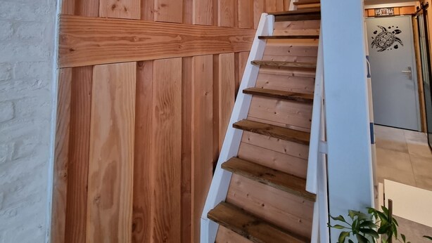 Un escalier en bois avec une rampe blanche et un tableau accroché au mur.
