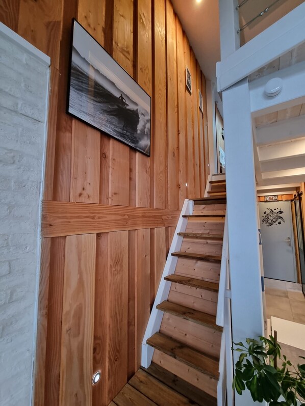 Een houten trap met een witte leuning en een schilderij aan de muur.