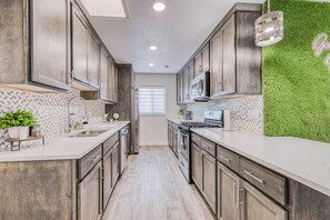 A kitchen with wooden cabinets, a microwave, and a green wall.