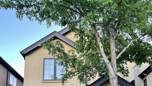A two-story residential building with a beige facade, a dark roof, and a front entrance with a door and windows. - Cheerful 2 Bedroom Home in Eugene (Eugene)