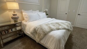 A bedroom with a bed, a nightstand, a lamp, a dresser, and a door. - Cheerful 2 Bedroom Home in Eugene (Eugene)