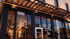 A building with a prominent entrance, large windows, and a sign that reads 'BOXSTEL'. - Boxstel - Moderns Stay Hotel (El Paso)