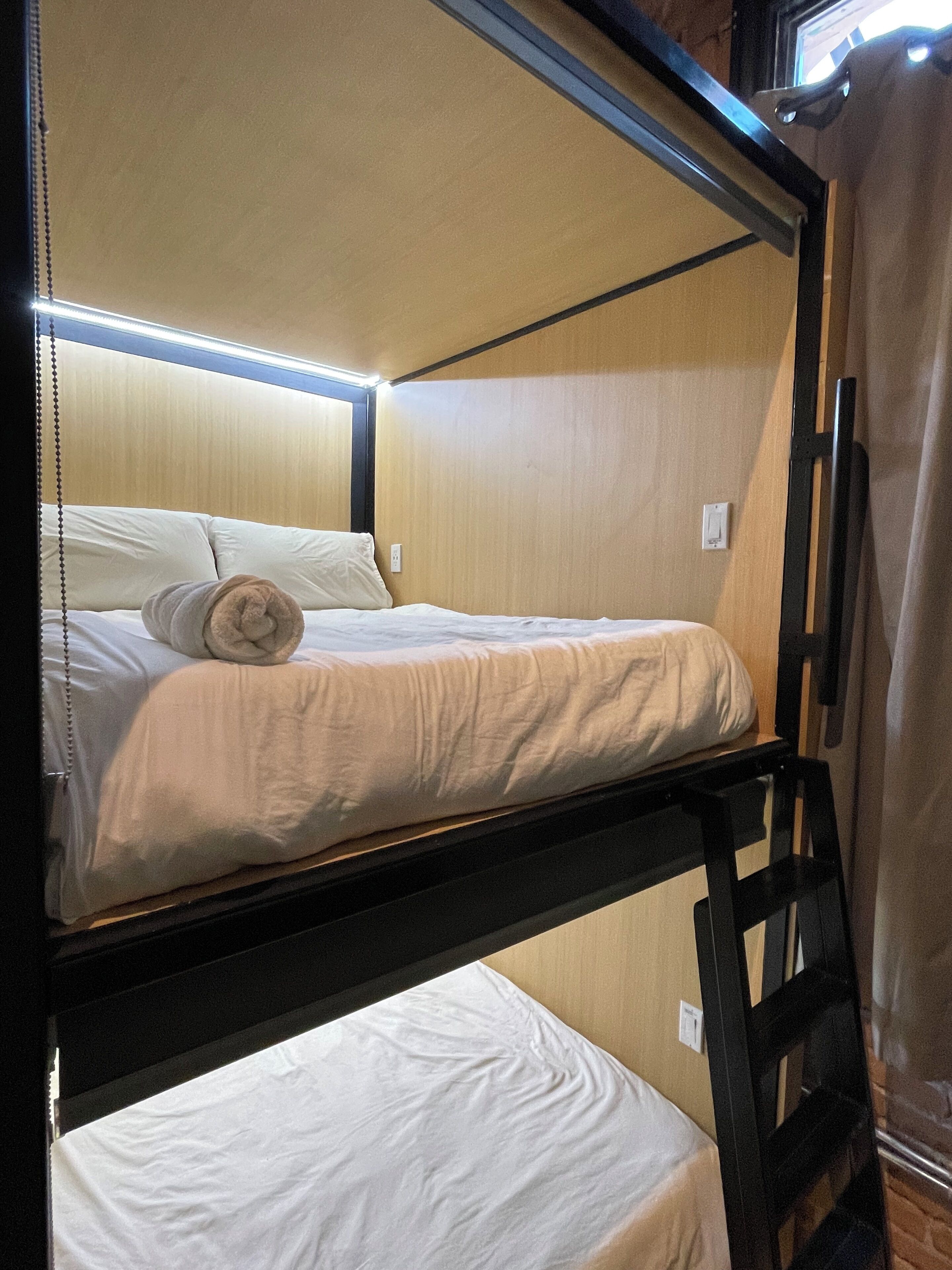 A bunk bed with a wooden frame and a curtain on the right side.